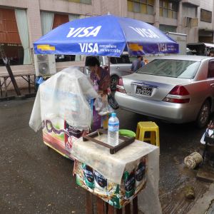 Street vendor under Visa umbrella, on phone