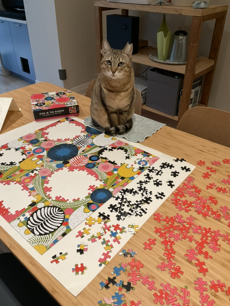 cat sitting beside partially done puzzle