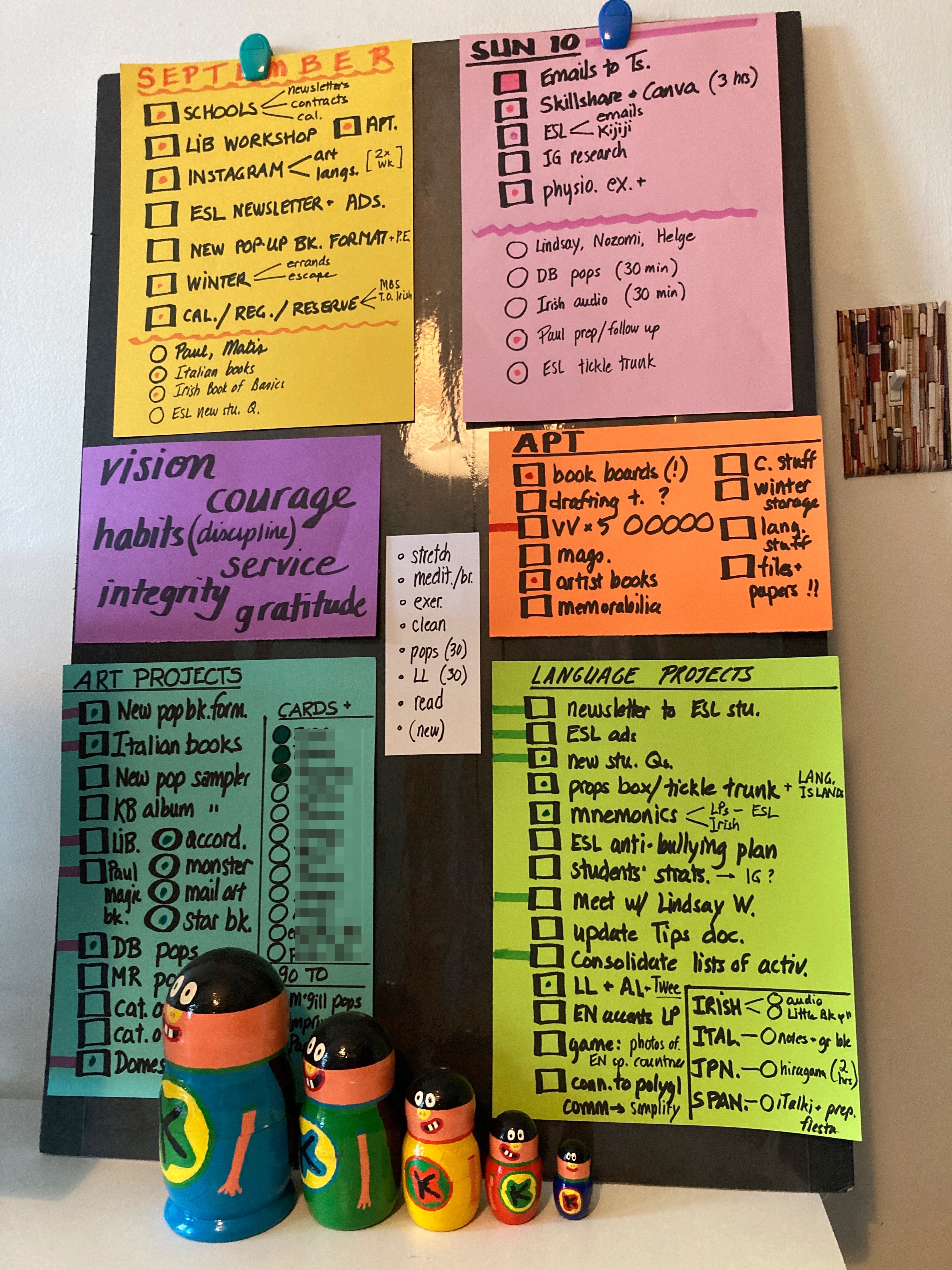 Coloured pieces of paper glued to a foam core backing. Each piece of paper has a different type of list with checkboxes next to each item.